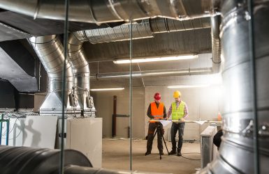 Workers making final touches to HVAC system. HVAC system stands for heating, ventilation and air conditioning technology. Team work, HVAC, indoor environmental comfort concept photo.